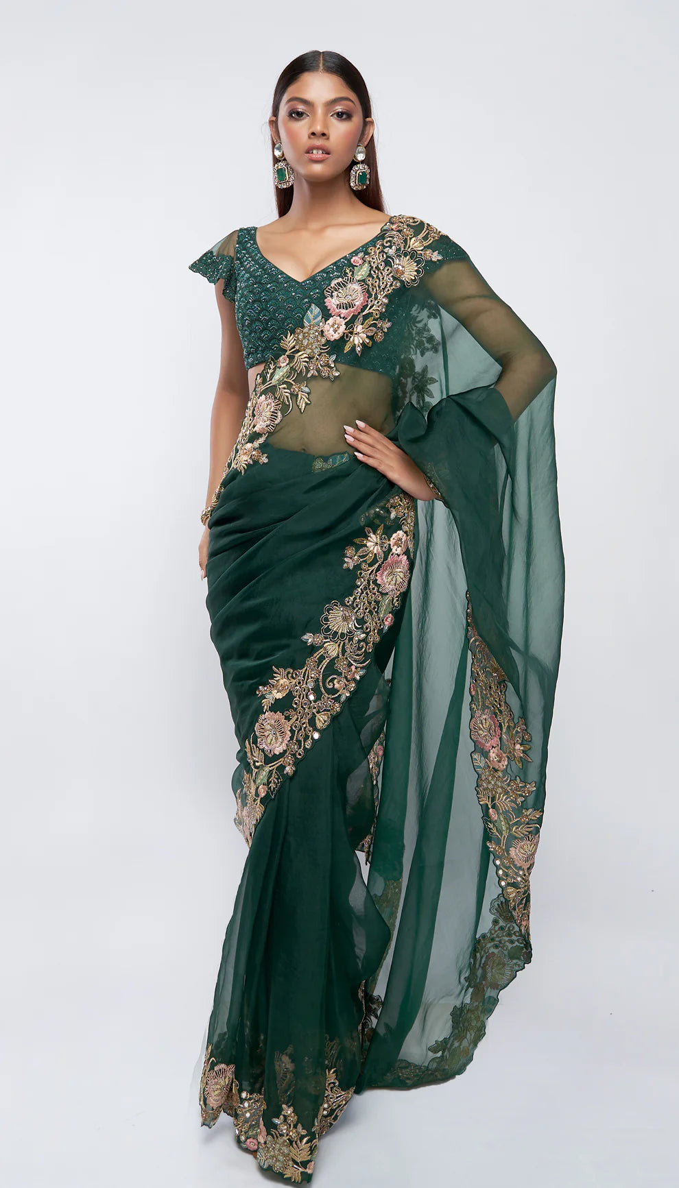 Woman in a green saree with gold embroidery against a white background for designers Shyamal and Bhumika.