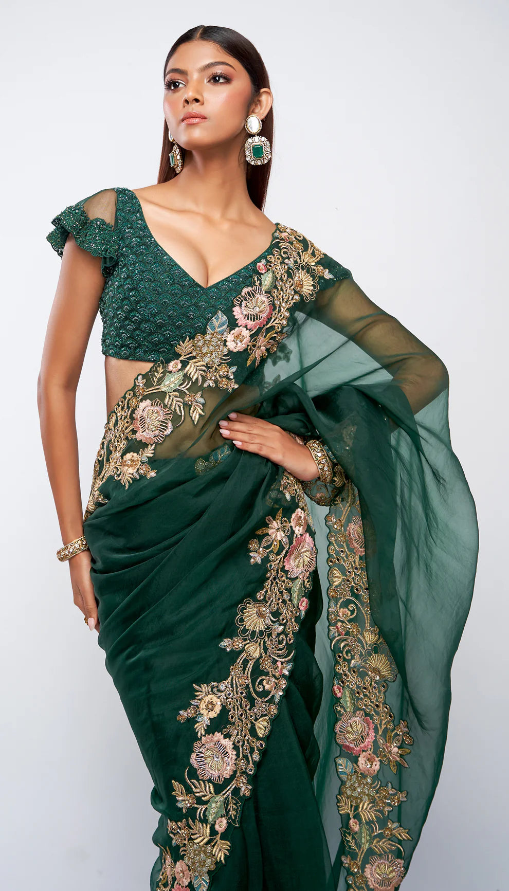 Woman in a green saree with gold embroidery against a white background for designers Shyamal and Bhumika.