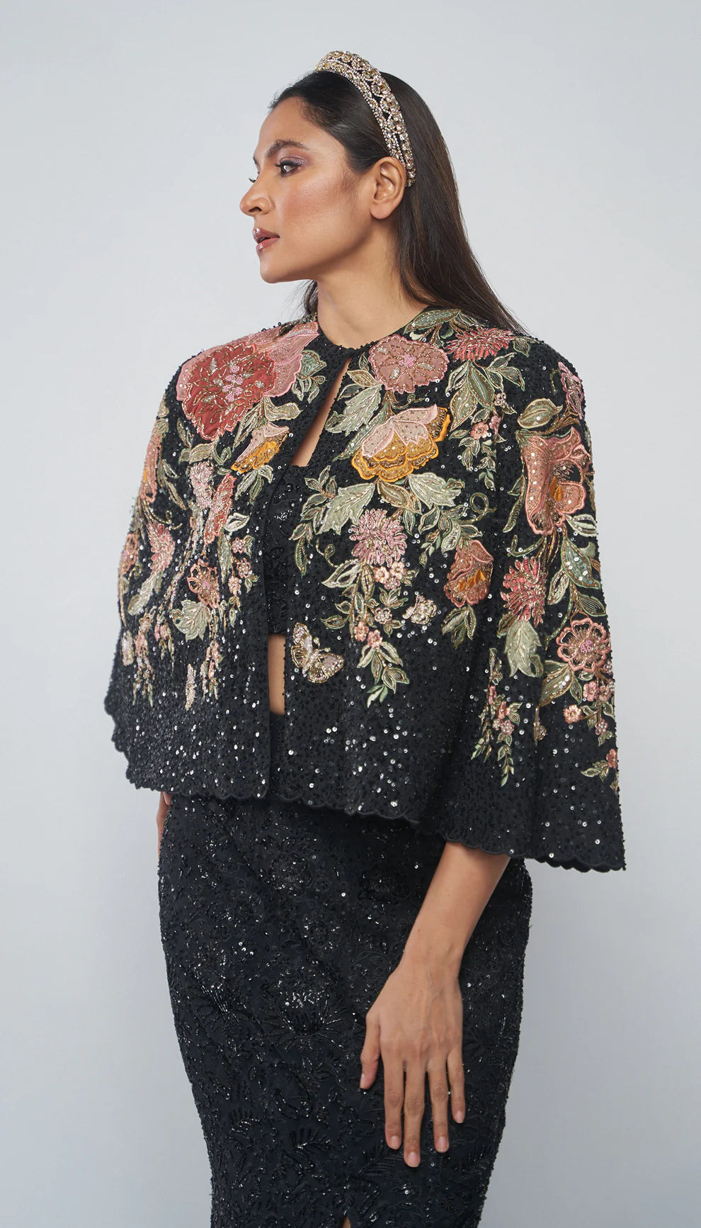 Charcoal black, crepe silk cape, florals, rose gold zardozi, glass beads, sequins, matching crop top, fluted skirt, tonal embroidery, black cape, evening celebrations, cocktail gatherings, wedding