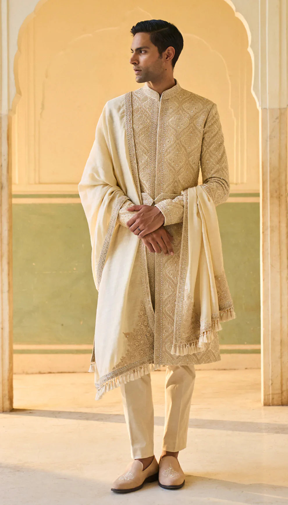 Man wearing a traditional ivory sherwani with a matching shawl by designers Shyamal and Bhumika, against a neutral background
