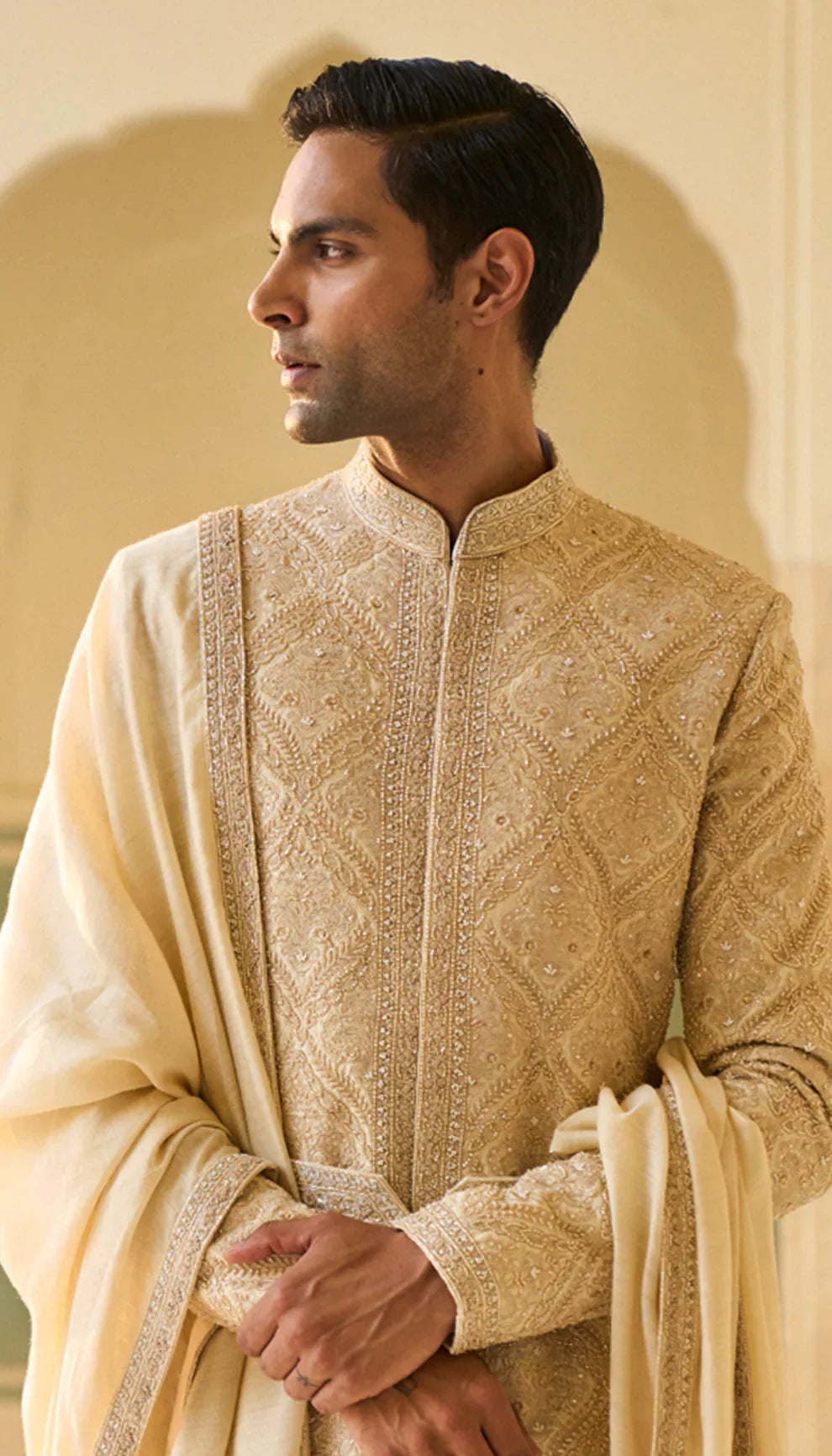 Man wearing a traditional ivory sherwani with a matching shawl by designers Shyamal and Bhumika, against a neutral background