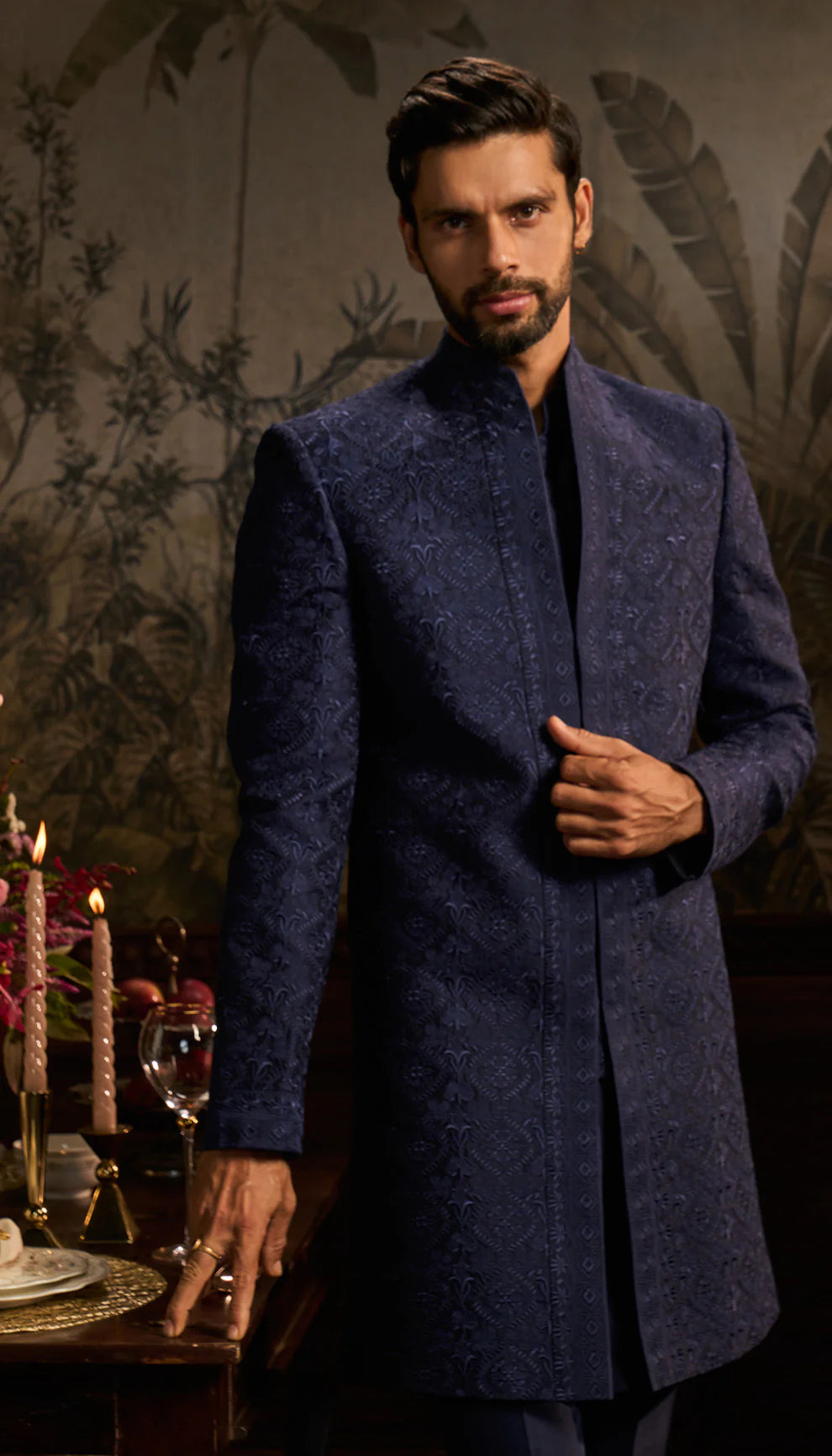 Man wearing a blue traditional jacket by designers Shyamal and Bhumika in an elegant interior setting