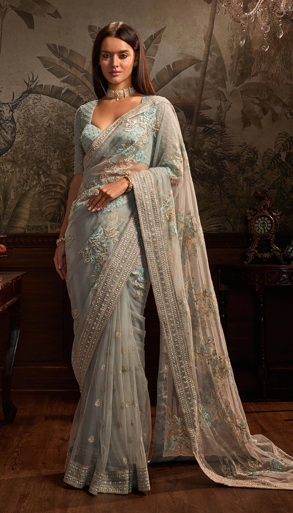 Woman wearing a light blue net saree with a matching blouse by designers Shyamal and Bhumika in a decorative setting.