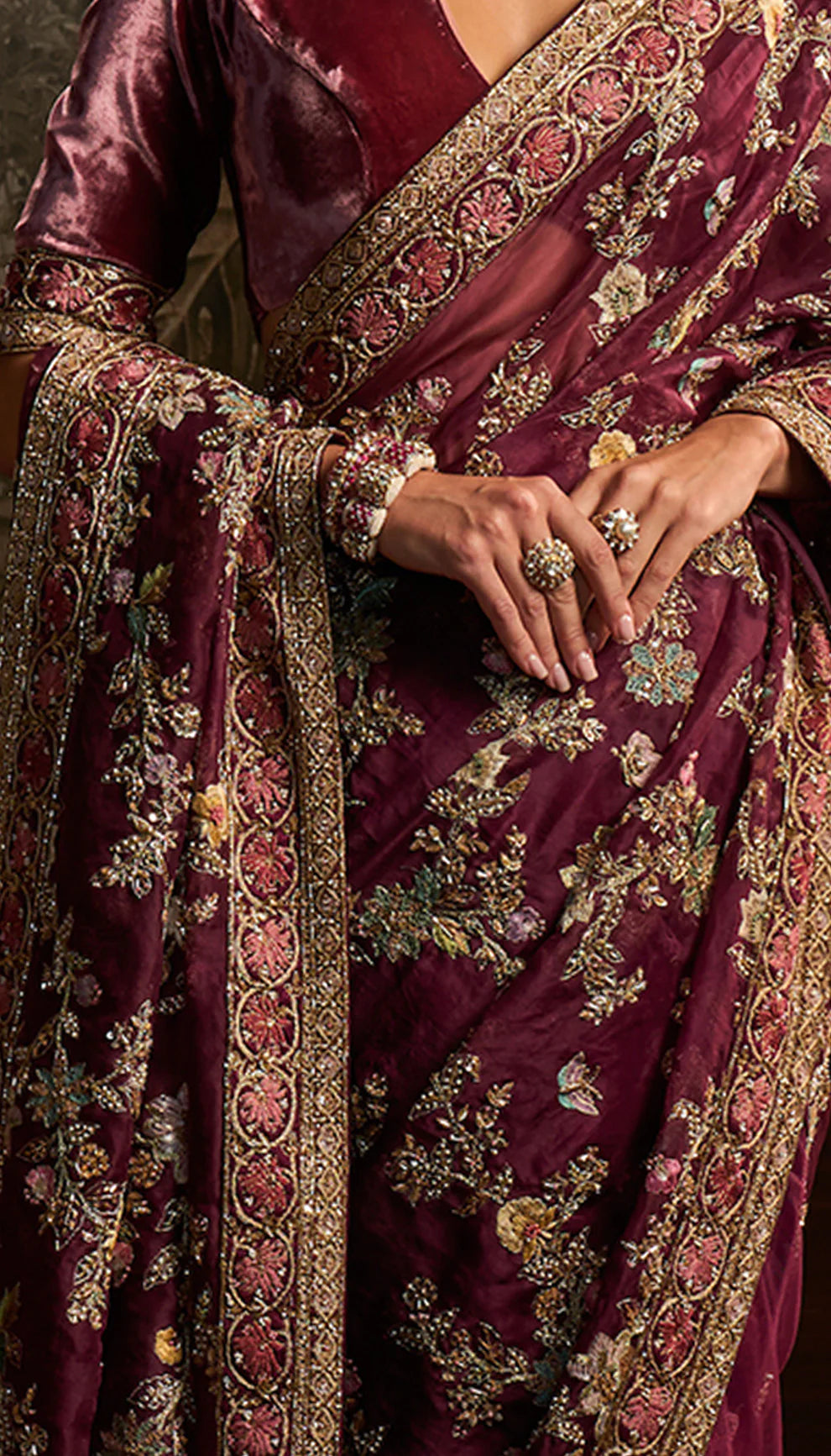 Woman wearing a purple saree with floral patterns by designers Shyamal and Bhumika in a decorative setting