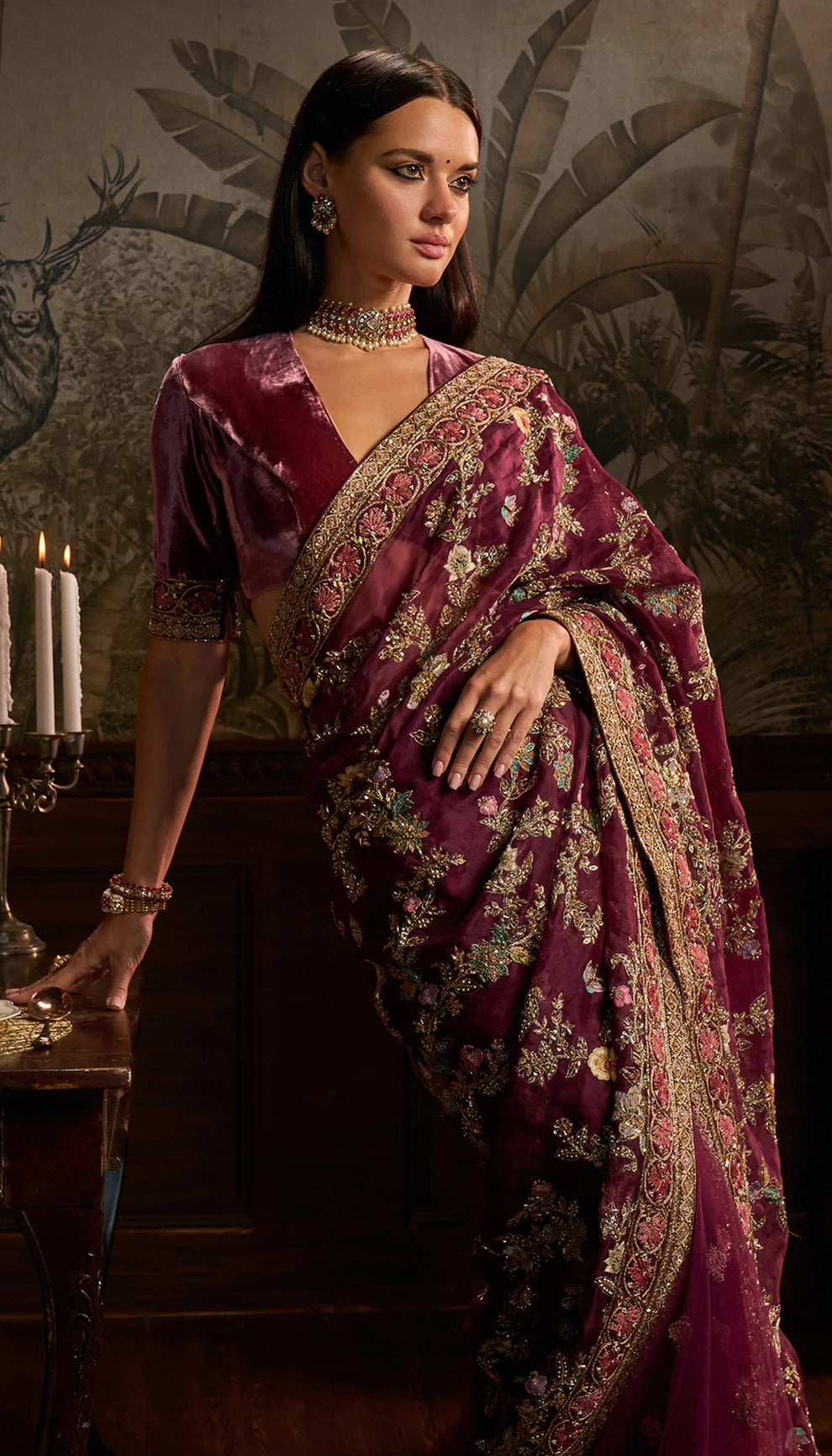 Woman wearing a purple saree with floral patterns by designers Shyamal and Bhumika in a decorative setting