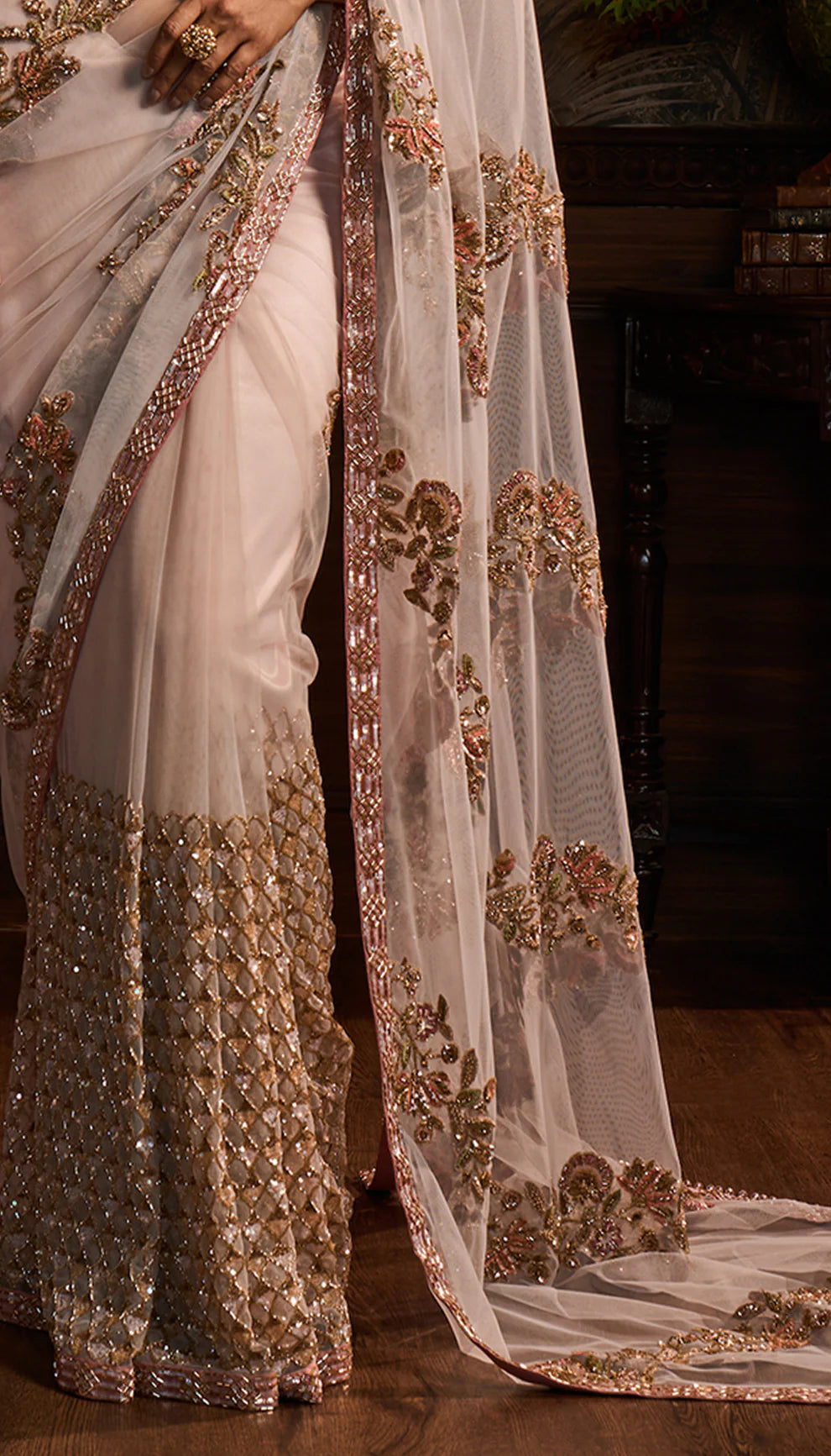 Woman wearing a Shyamal and Bhumika designer traditional saree with intricate designs in a decorative setting.