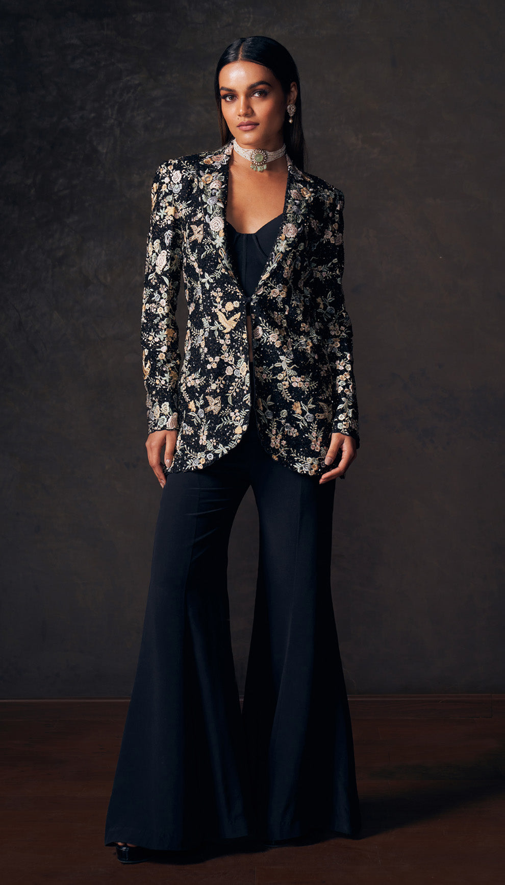 Woman wearing a floral jacket and dark pants by designers Shyamal and Bhumika against a dark background