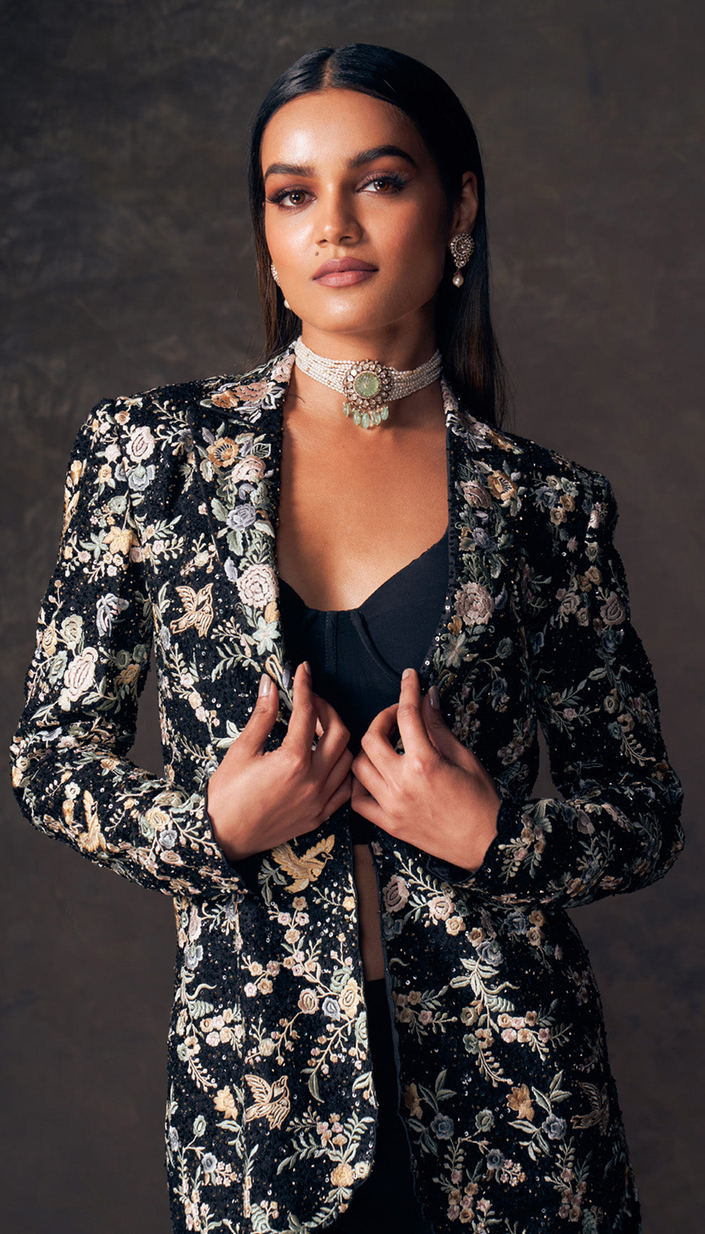 Woman wearing a floral jacket and dark pants by designers Shyamal and Bhumika against a dark background