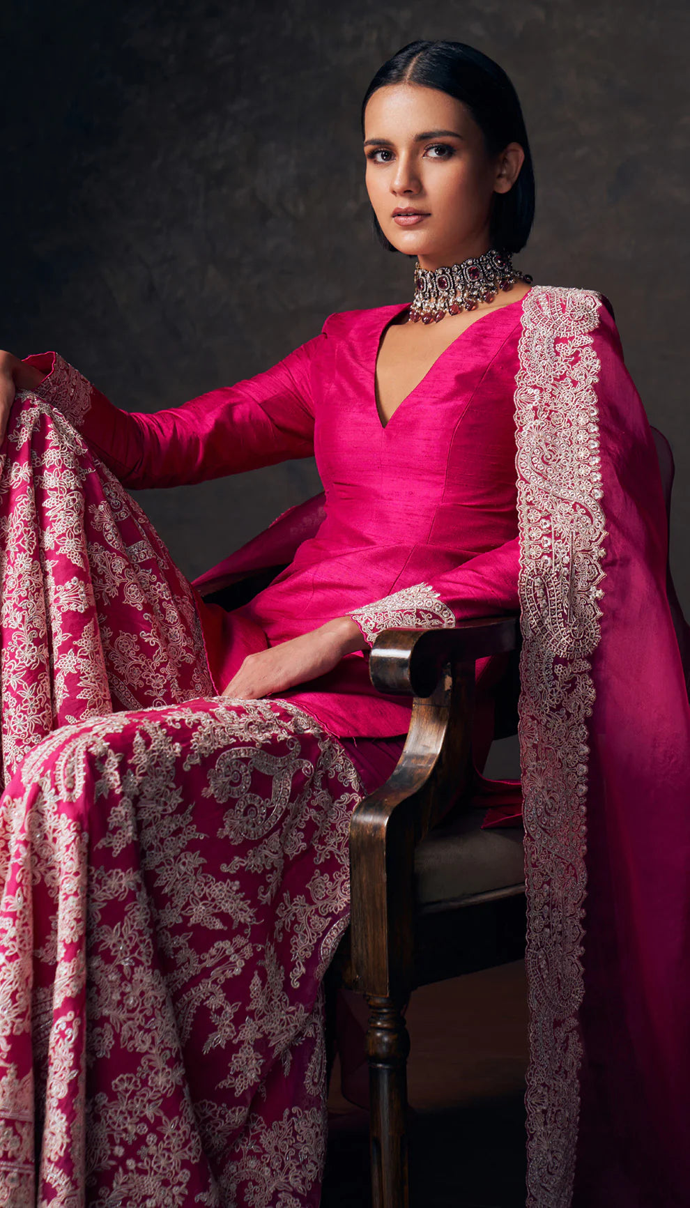 Woman wearing a pink traditional sharara set with a patterned dupatta by designers Shyamal and Bhumika against a dark background