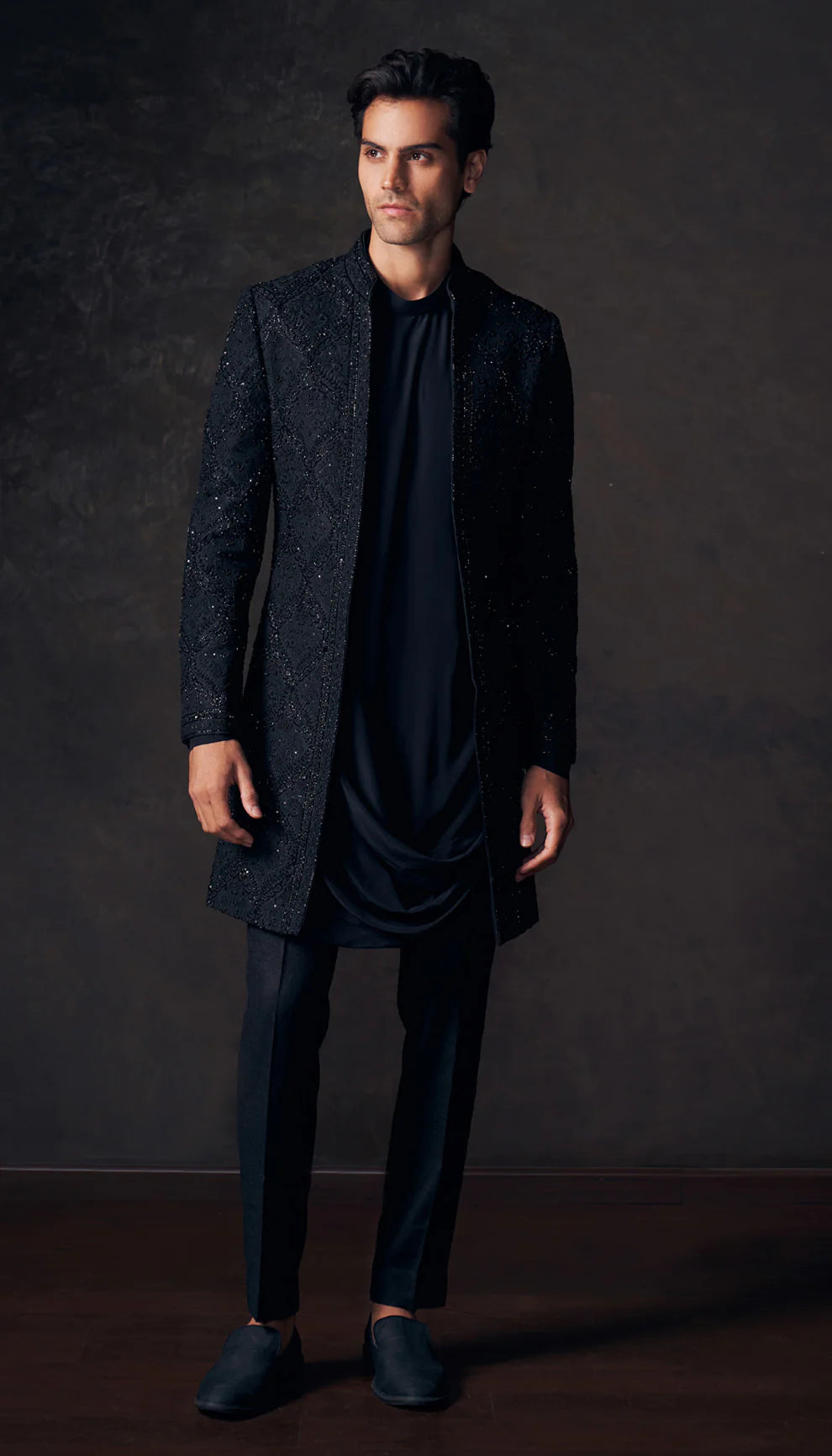 Man wearing a dark jacket by designers Shyamal and Bhumika against a dark background