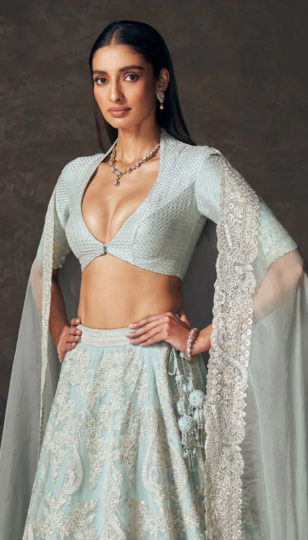Woman in a light blue traditional lehenga by designers Shyamal and Bhumika with a dark background