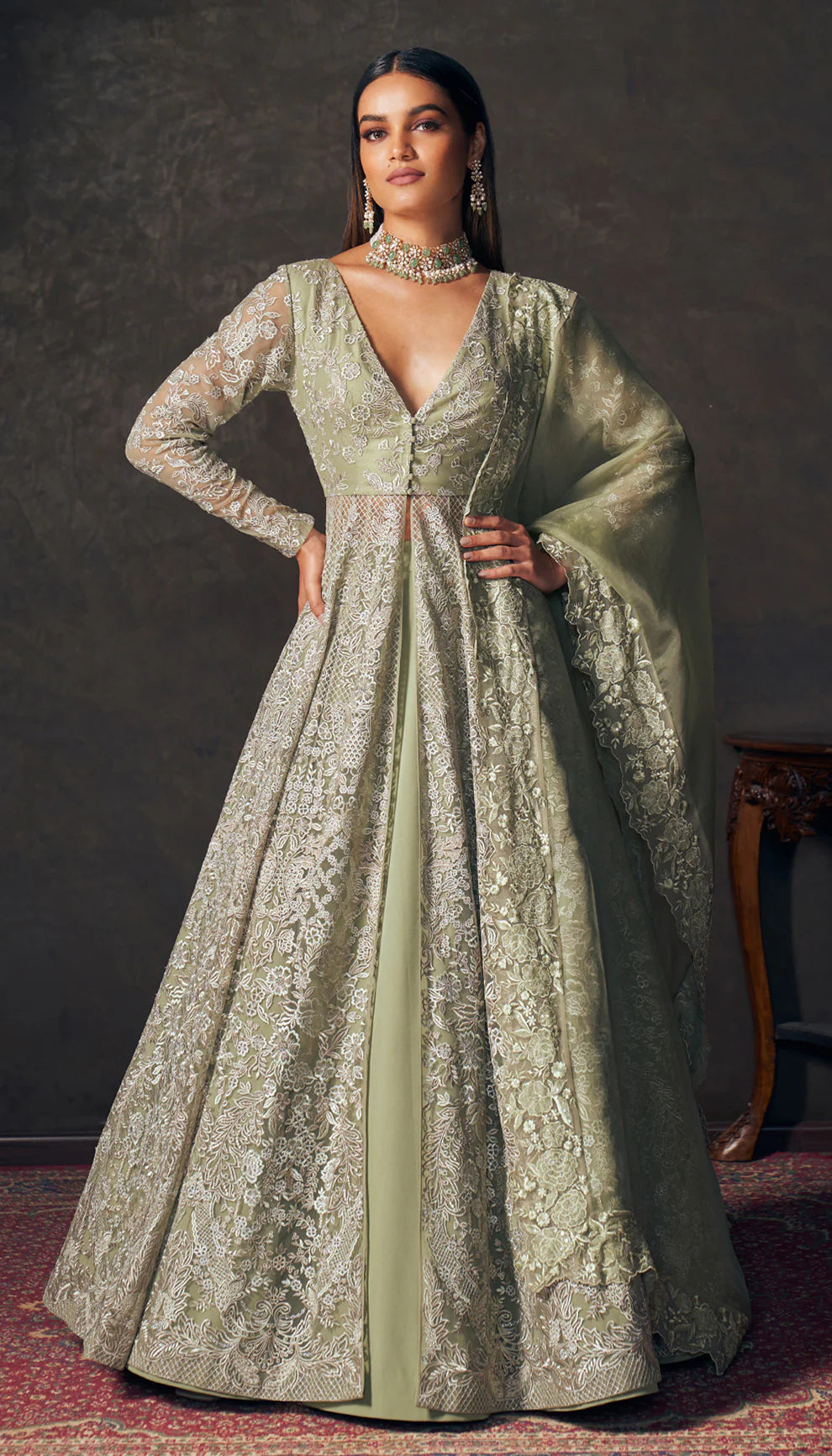 Woman wearing an olive green embroidered jacket by designers Shyamal and Bhumika with a dark background