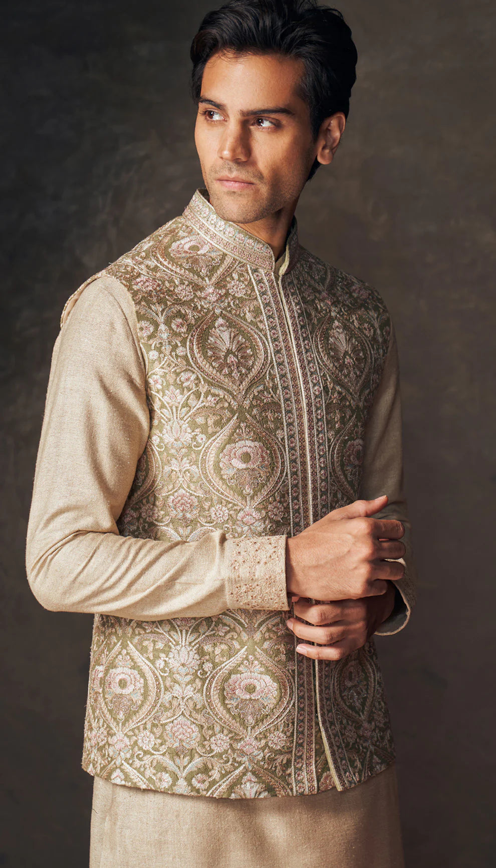 Man wearing a traditional beige embroidered bandi kurta set with white pants by designers Shyamal and Bhumika against a dark background