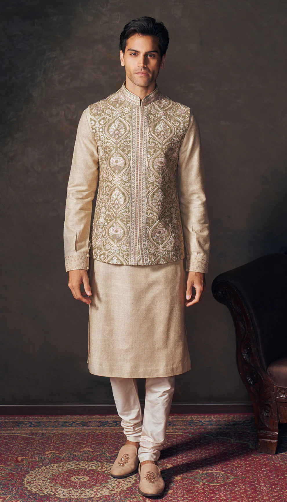 Man wearing a traditional beige embroidered bandi kurta set with white pants by designers Shyamal and Bhumika against a dark background