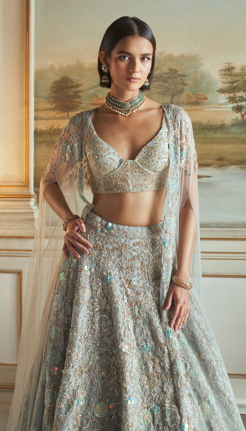 Frost blue, tulle net lehenga, floral embroidery, resham, sequins, glass beads, crystals, sheer tulle net corset blouse, embroidered cape, light blue lehenga, weddings, festive celebrations, evening receptions, destination wedding, sangeet, haldi, mehndi, reception, bridal wear, festive wear, occasion wear, blue lehenga, blue designer lehenga, pastel blue designer lehenga, blue resham work designer lehenga