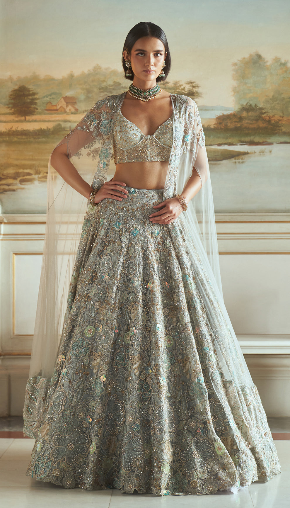 Frost blue, tulle net lehenga, floral embroidery, resham, sequins, glass beads, crystals, sheer tulle net corset blouse, embroidered cape, light blue lehenga, weddings, festive celebrations, evening receptions, destination wedding, sangeet, haldi, mehndi, reception, bridal wear, festive wear, occasion wear, blue lehenga, blue designer lehenga, pastel blue designer lehenga, blue resham work designer lehenga