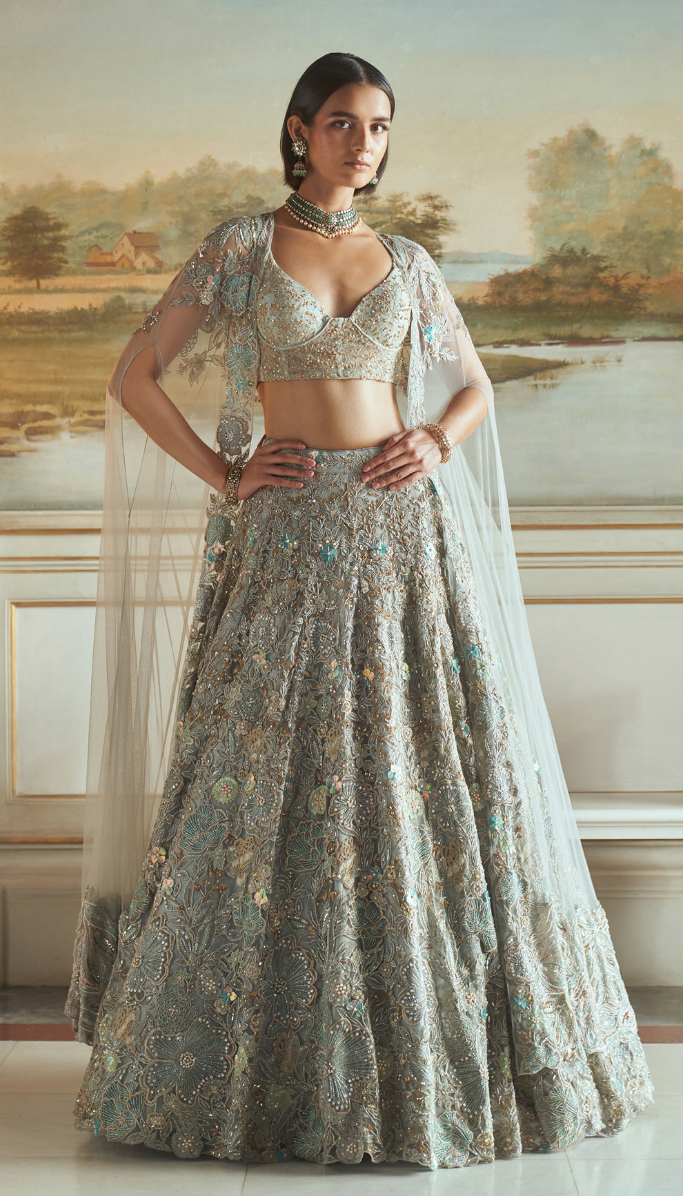 Frost blue, tulle net lehenga, floral embroidery, resham, sequins, glass beads, crystals, sheer tulle net corset blouse, embroidered cape, light blue lehenga, weddings, festive celebrations, evening receptions, destination wedding, sangeet, haldi, mehndi, reception, bridal wear, festive wear, occasion wear, blue lehenga, blue designer lehenga, pastel blue designer lehenga, blue resham work designer lehenga
