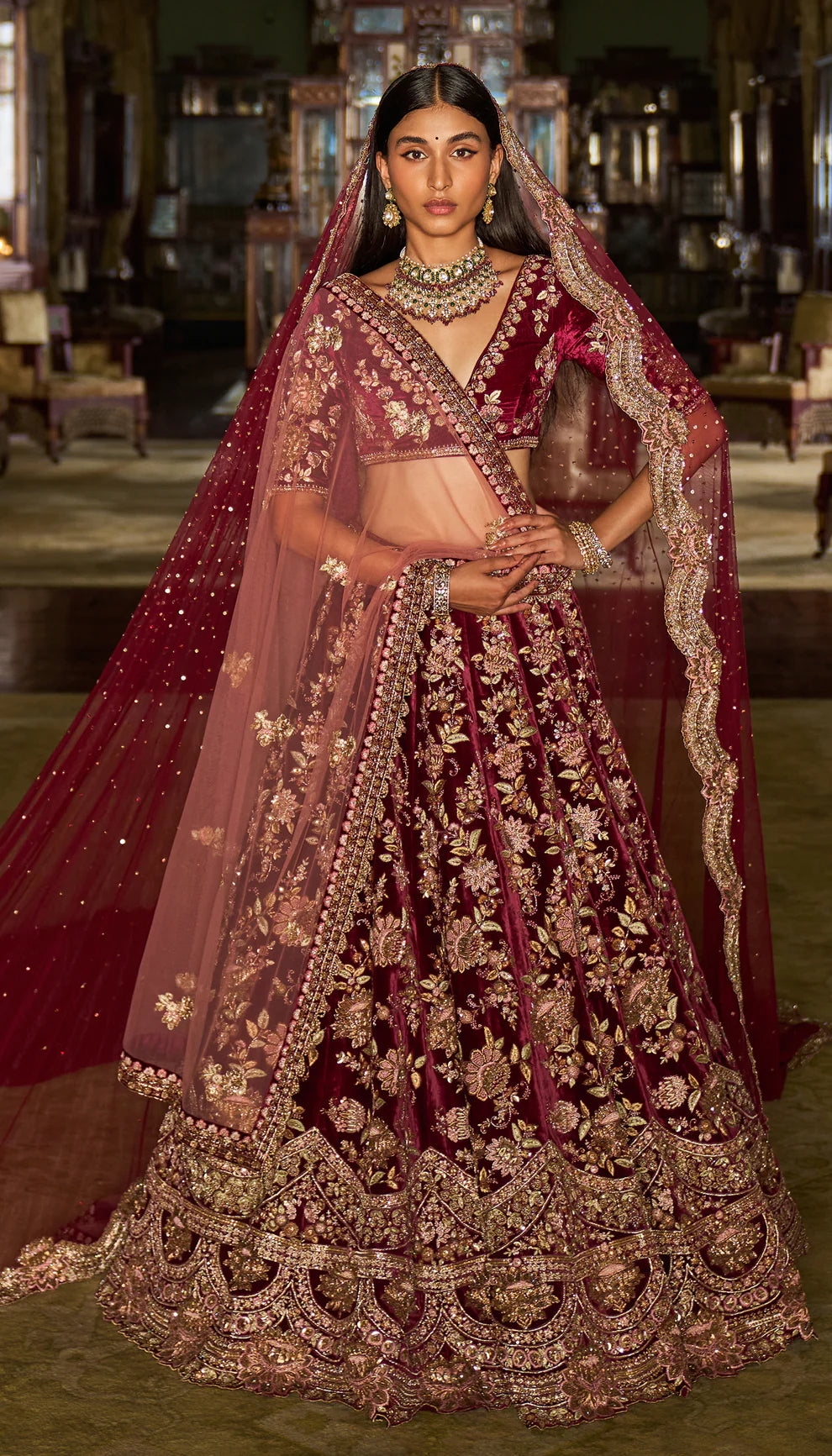 Woman in a traditional maroon and gold embroidered velvet lehenga with a matching dupatta by designers Shyamal and Bhumika.