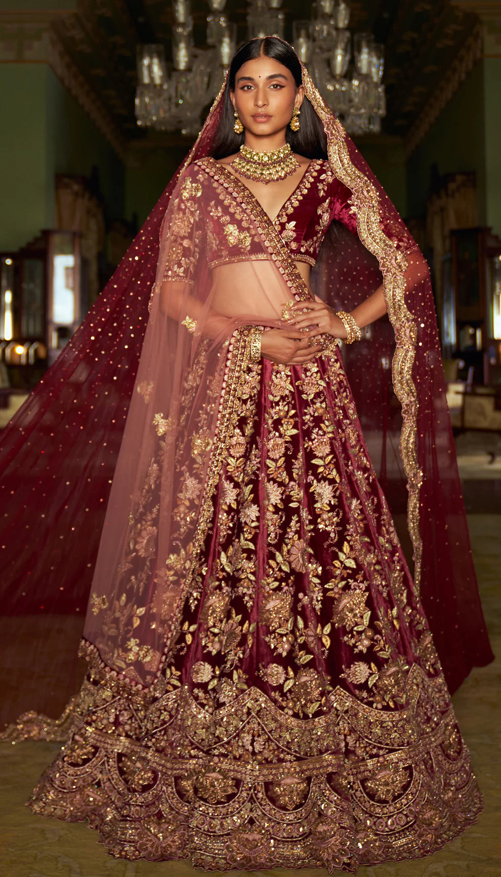 Woman in a traditional maroon and gold embroidered velvet lehenga with a matching dupatta by designers Shyamal and Bhumika.