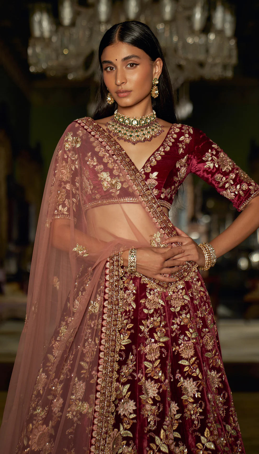 Woman in a traditional maroon and gold embroidered velvet lehenga with a matching dupatta by designers Shyamal and Bhumika.