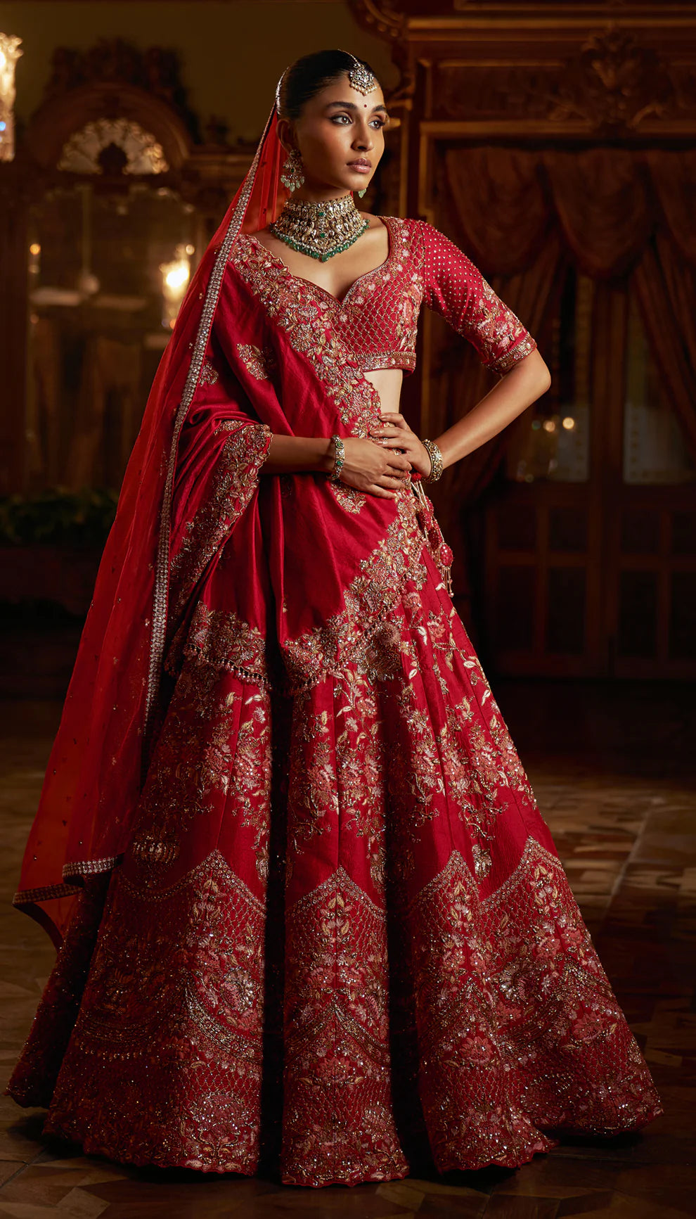 Woman in a red and gold embroidered traditional bridal lehenga with a matching dupatta by designers Shyamal and Bhumika