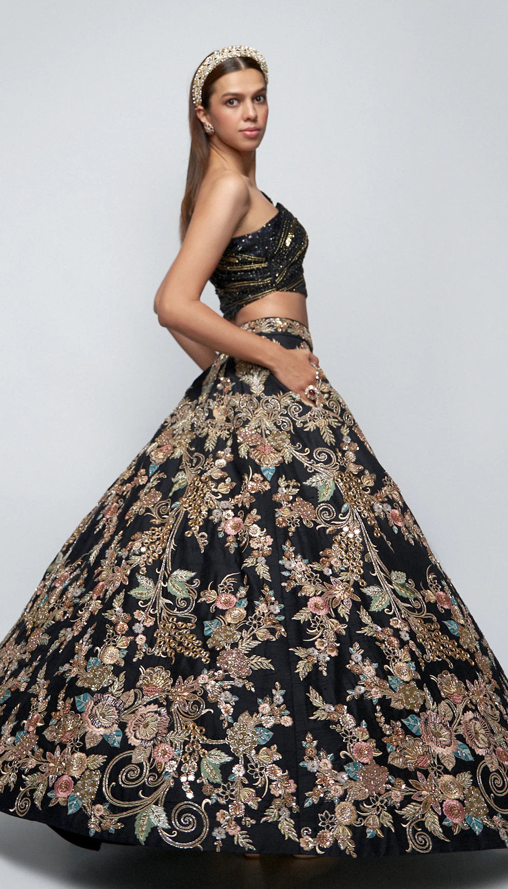 Woman wearing black and gold lehenga against a white background for designers Shyamal and Bhumika.