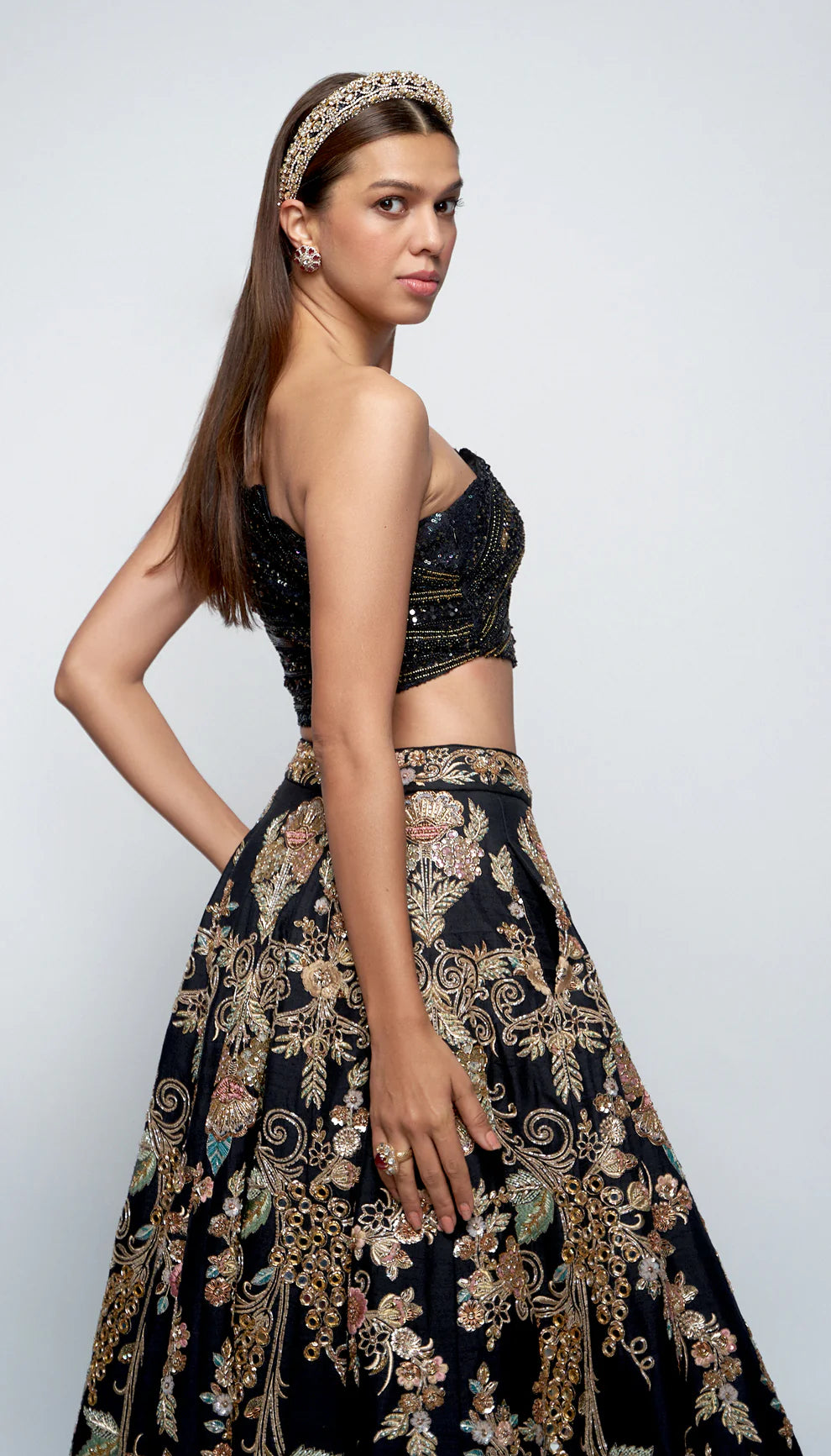 Woman wearing black and gold lehenga against a white background for designers Shyamal and Bhumika.