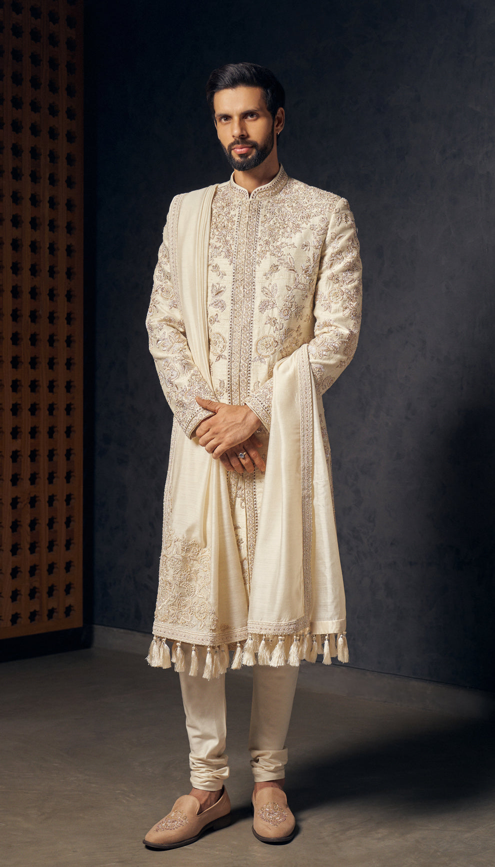 An ivory raw silk sherwani featuring intricate rose gold zardozi and resham embroidery,