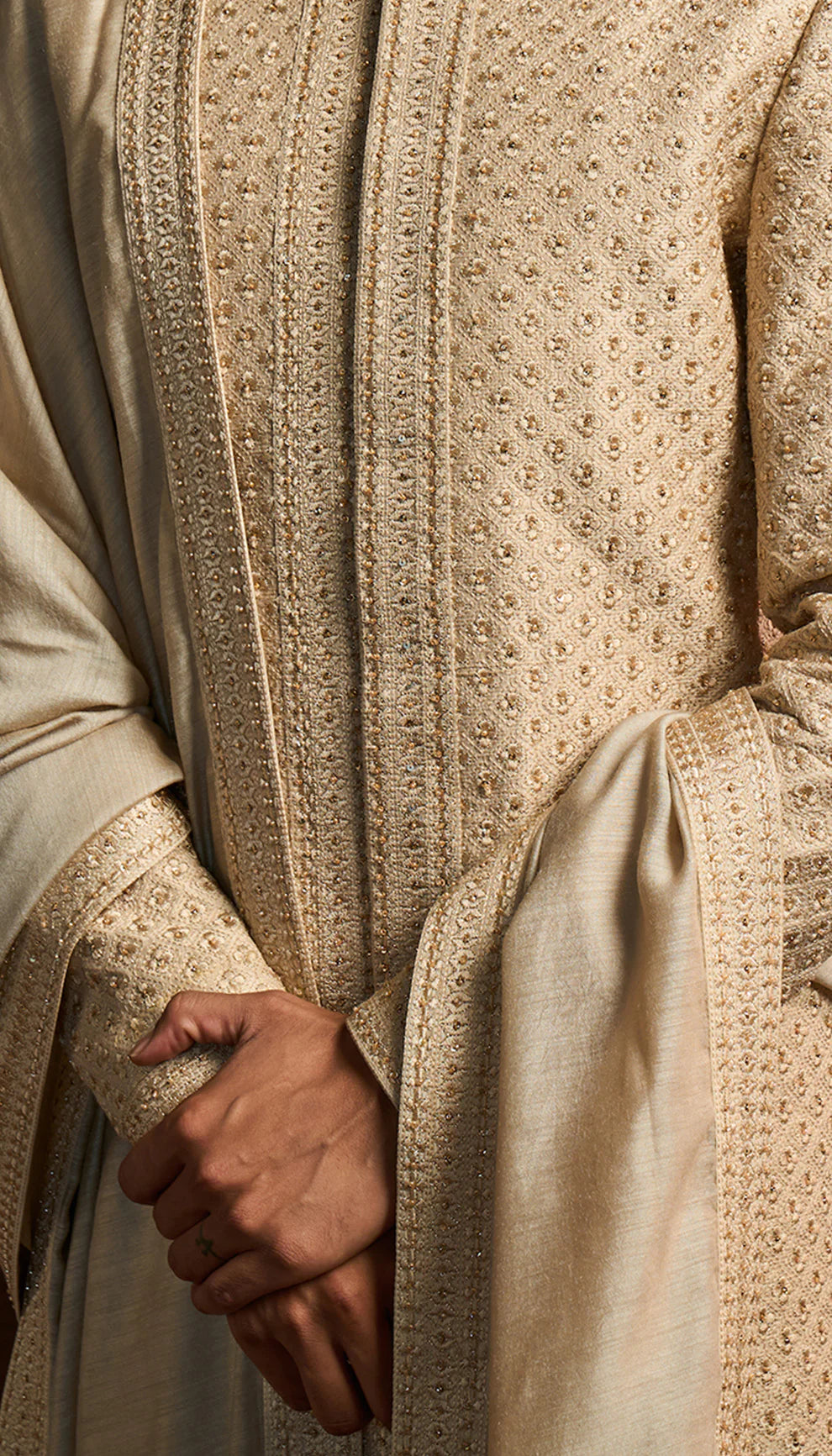 Man wearing a Shyamal and Bhumika ivory sherwani with white pants in an ornate room.