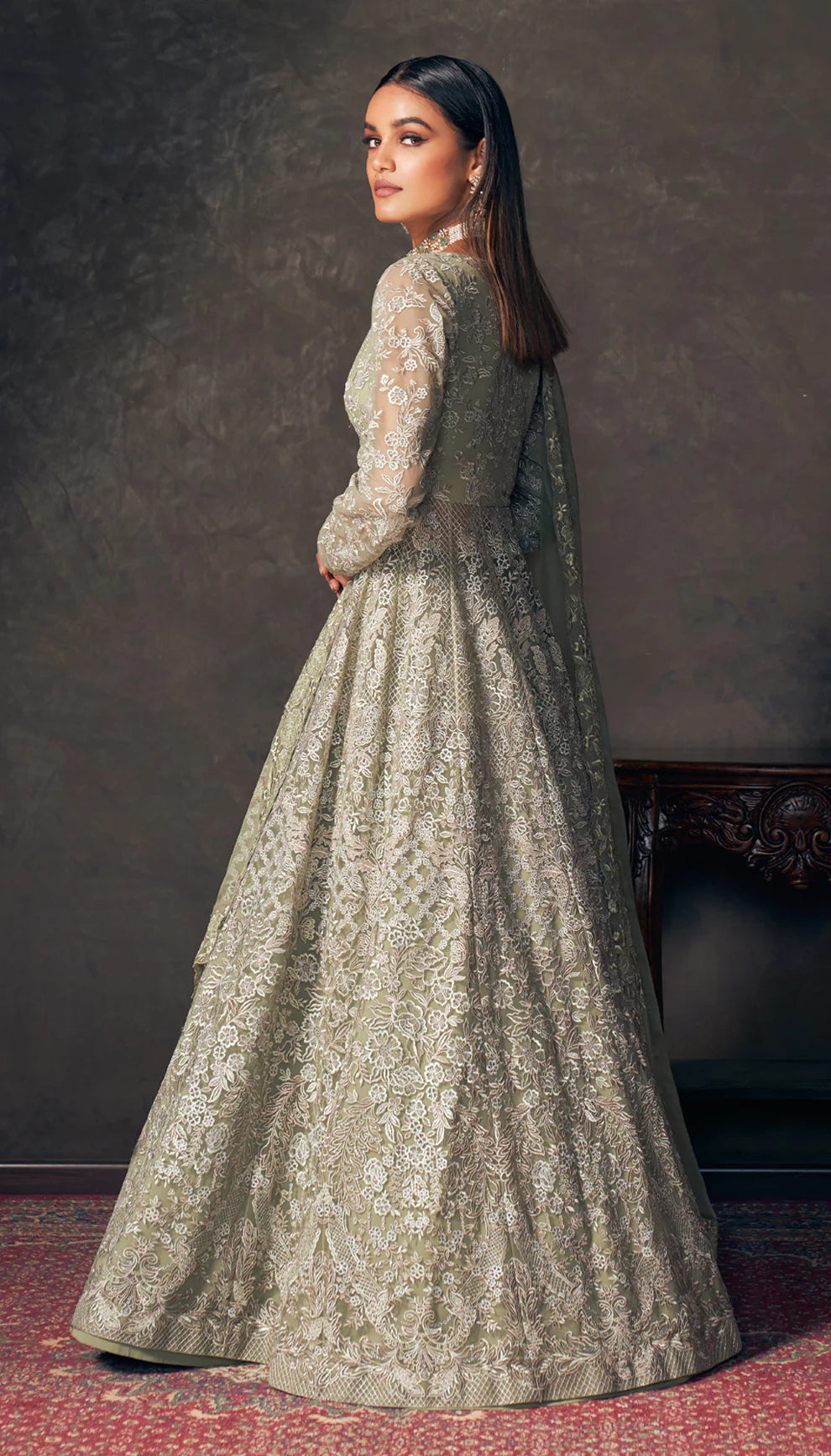 Woman wearing an olive green embroidered jacket by designers Shyamal and Bhumika with a dark background