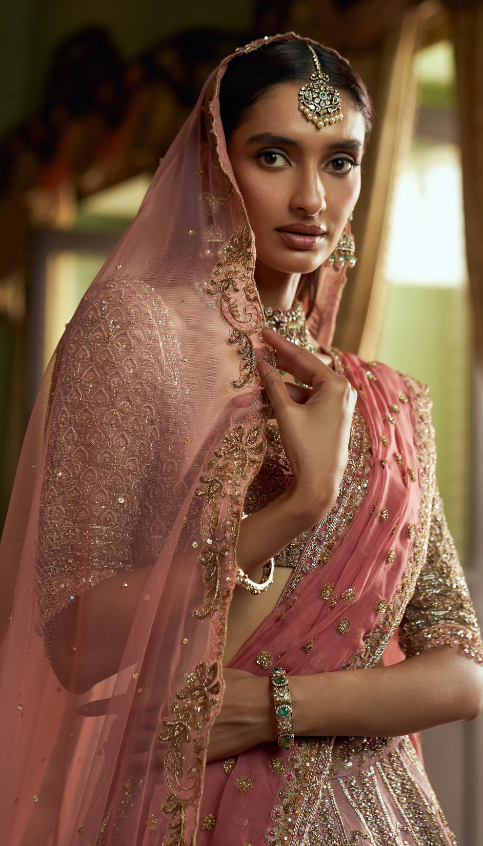 Rose pink, raw silk lehenga, architectural- inspired motifs, zardozi, aari work, sheer tulle net choli, tulle net matching dupatta, pink bridal lehenga, weddings, festive celebrations, evening receptions